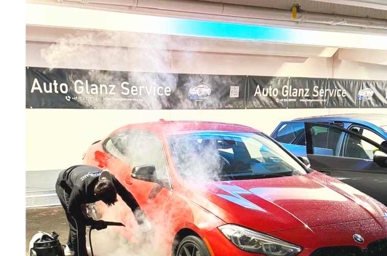 Rotes Auto wird im Parkhaus mit Dampfstrahl gereinigt